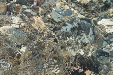 Clear water and colorful pebbles on the sea