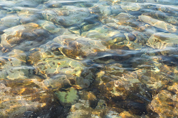 Fototapeta na wymiar Clear water and colorful pebbles on the sea