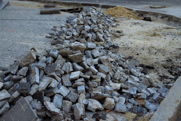 heaps of paving stones lie on the road, laying stones, unfinished work. road pedestrian area