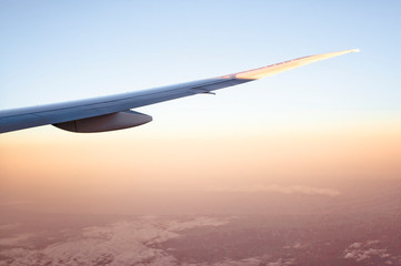 Fototapeta na wymiar Airplane Wing over Hazy Red Landscape