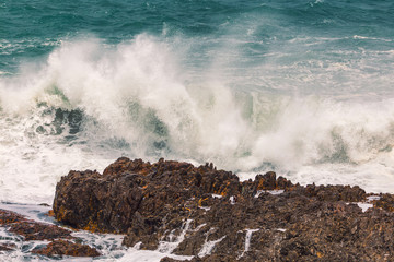 Huge wave crashing rocky coastline in Hermanus, South Africa