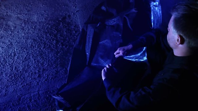 Policeman looking at victim face and zipping body bag, murder crime scene