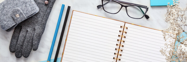 Panoramic top view workspace mockup on blue and marble background with notebook, gloves, pencils, glasses and accessories. .
