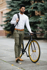 Young handsome asian business man with backpack walking down the street pushing bicycle while going to work.