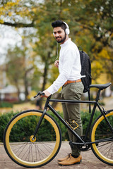 Indian Businessman listening to music while walking to office with his bike. Man enjoying his commute to office walking with his bicycle