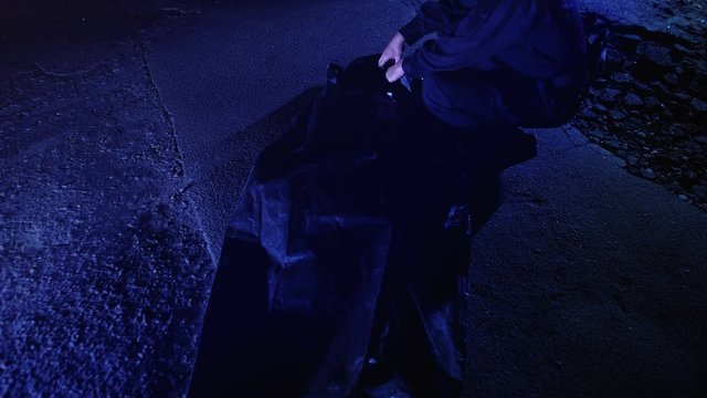 Policeman opening body bag with corpse, looking at victim, murder crime scene