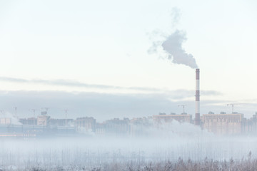 city buildings in the fog on an early winter morning. steam pipe in an urban environment. winter landscape city outskirts