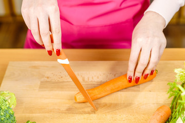 Obraz premium Woman cutting carrot on kitchen board