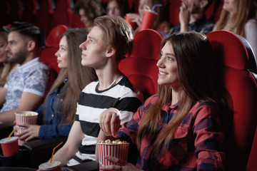 Girl in red shirt watching interesting film at cinema.