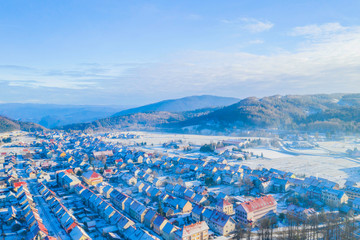 Fototapeta na wymiar Croatia, Delnice, Gorski kotar, panoramic view of town center from drone in winter, mountain landscape in background, houses covered with snow 