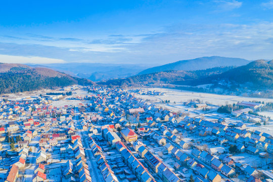 Croatia, Delnice, Gorski kotar, panoramic view of town center from drone in winter, mountain landscape in background, houses covered with snow 