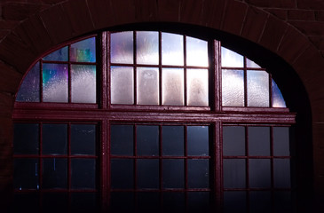 A photograph of a vintage dark window and the reflection of trees against its glass panes.