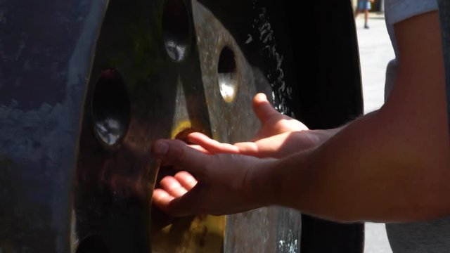Man's hands carefully touches a metal gong bell in Buddhist temple. Thailand.