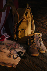 close-up view of trekking boots, hiking equipment, map, backpack and american flag on wooden surface