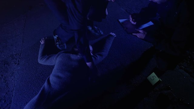 Policeman fixing position of corpse with chalk, crime scene investigation