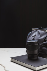 close-up view of photo lens on notebook and backpack on black