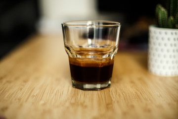 A glass of iced espresso lying on a wooden table