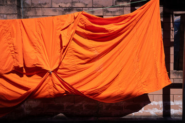 texture of orange robe of a buddhist monk or novice hanged on wire
