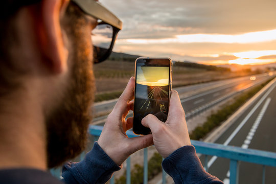 Guy Taking A Photo With His Mobile Phone At Sunset. Photo Style Social Networks