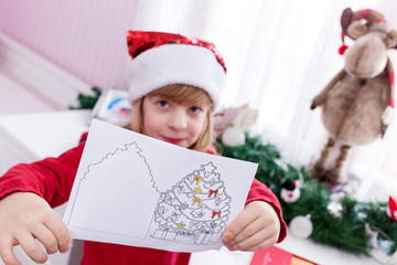 Cute, little blond-haired girl in red blouse showing her Christmas tree drawing