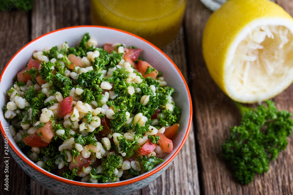 Wall mural Tabbouleh salad with bulgur, fresh parsley, tomatoes and  salad  dressing