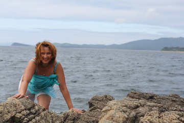 Fototapeta na wymiar happy young woman on the rocks by the sea