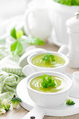 Broccoli soup in bowls on wooden kitchen table closeup. Healthy vegetarian dish. Diet food