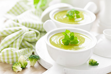 Broccoli soup in bowls on wooden kitchen table closeup. Healthy vegetarian dish. Diet food