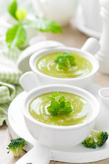 Broccoli soup in bowls on wooden kitchen table closeup. Healthy vegetarian dish. Diet food