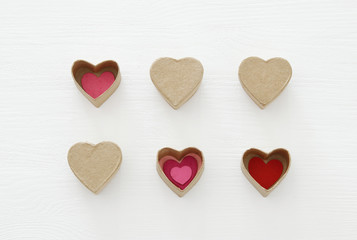 Obraz premium Valentine's day concept. hearts as paper gift boxes over wooden white background.