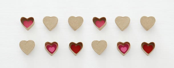 Valentine's day concept. hearts as paper gift boxes over wooden white background.