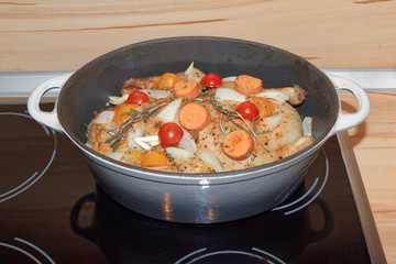 Roasting a duck with vegetables in a roaster on a hot plate.