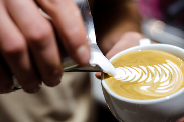 Closeup of making beautiful latte art with milk in an espresso cup