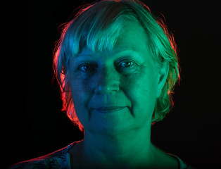Portrait of a woman with colored light and dark background.