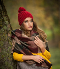 Happy Portrait fashion of a beautiful young Caucasian woman with a red cap and scarf and yellow pullover in autumn park,red green yellow threes. Autumn, season and people concept.Autumn lifestyle