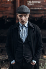 Fototapeta na wymiar stylish man in retro outfit, posing on background of railway. england in 1920s theme. fashionable look of brutal confident man. atmospheric moments