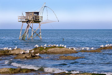 Fototapeta na wymiar Fishing carrelet with the seagulls on the rocks at Saint-Michel-Chef-Chef in the Loire-Atlantique department in western France.