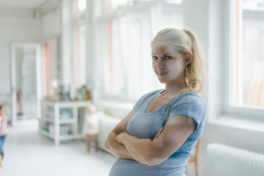Portrait of smiling pregnant woman in a bright room