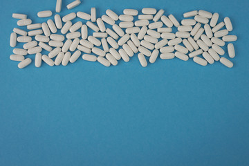 Blue background with many white pills in the top and empty space from the bottom