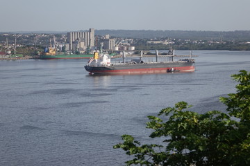 A freight ship guided into port by a harbor tug in Havana Cuba