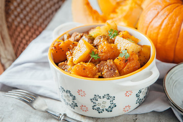 Pumpkin and turkey stew in a beautiful dish on the background of fresh pumpkin - obrazy, fototapety, plakaty