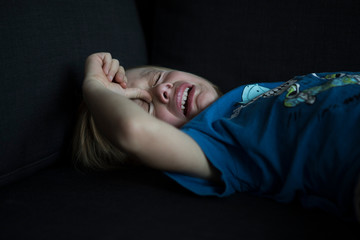 Crying boy lying on couch