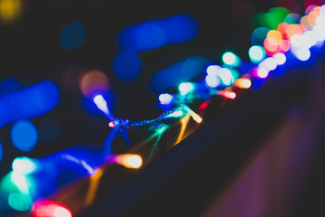 string of multicolored fairy lights on house terrace with bokeh effect