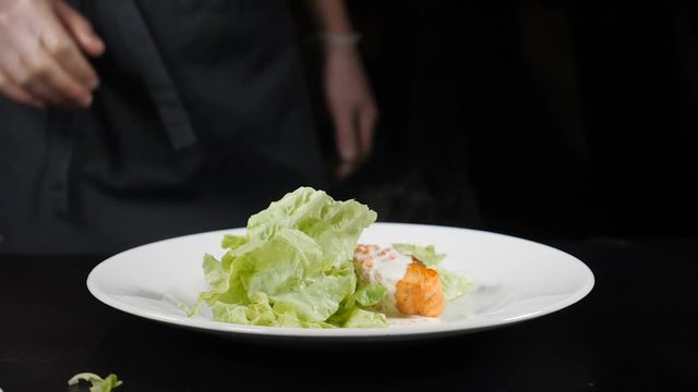 Lettuce leaf falling down in slow motion on dish with freshfried salmon fillet placed on white plate. Fine dining concept. hd