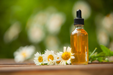 Essence of flowers on table in beautiful glass bottle