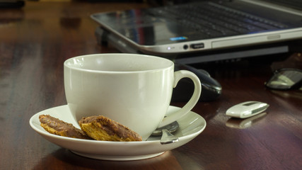 traditional tea and biscuits near laptop and accessories on wooden desk 