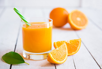 Orange juice and fresh oranges on wooden table