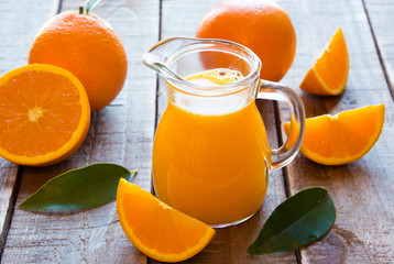 Orange juice and fresh oranges on wooden table