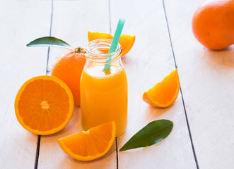 Orange juice and fresh oranges on wooden table