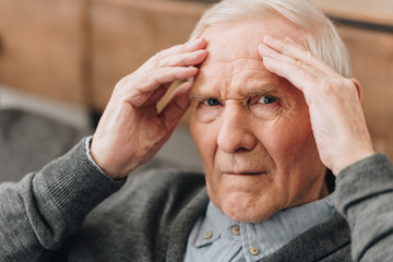 retired man holding head while having headache - obrazy, fototapety, plakaty